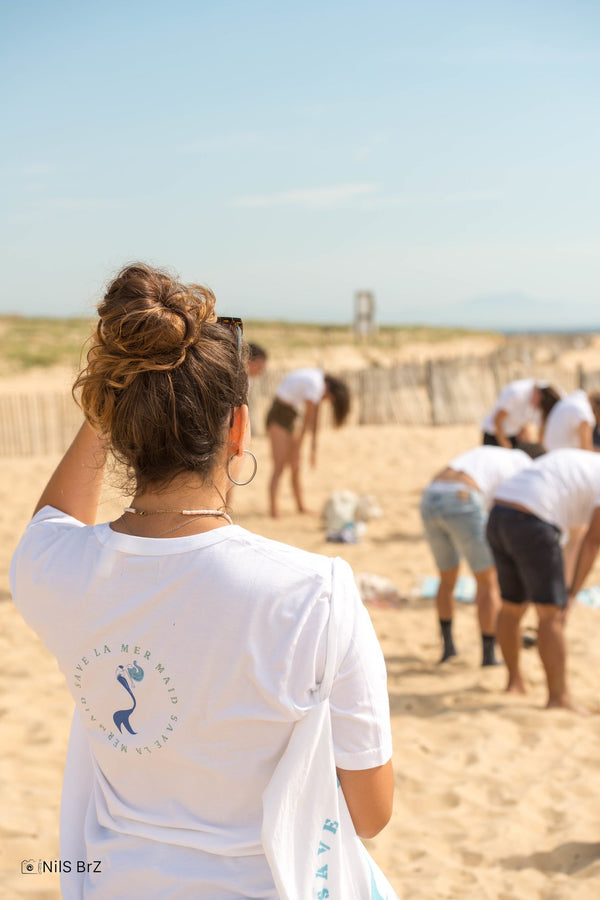 Volunteer ‘Save La Mermaid’ seen from behind on the beach
