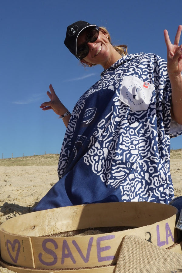Maud Le Car wearing a Save La Mermaid poncho on the beach