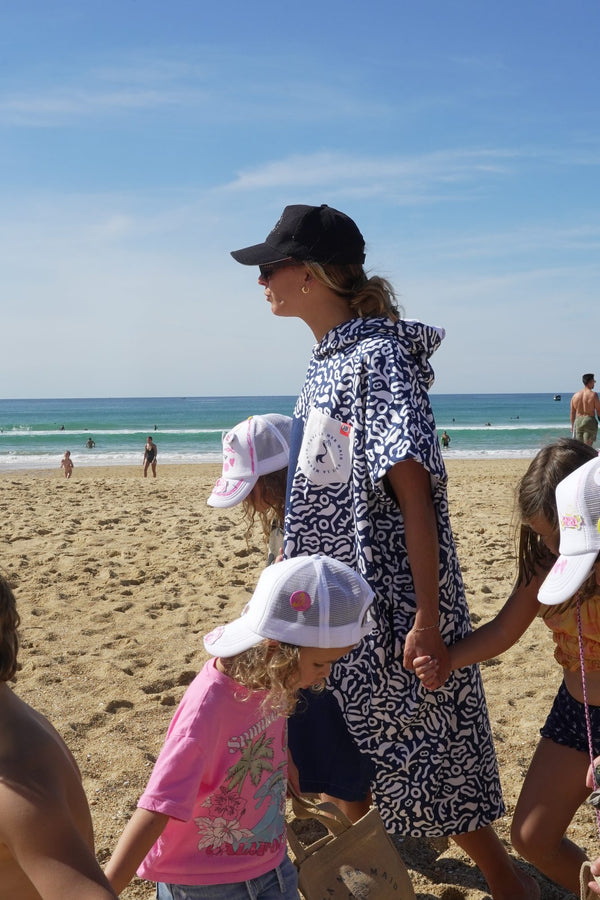 Maud Le Car wearing a Save La Mermaid poncho on the beach during Mermaid Day